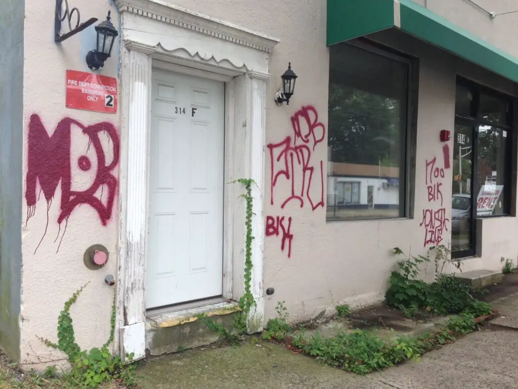 Gang graffiti on front of a store and house
